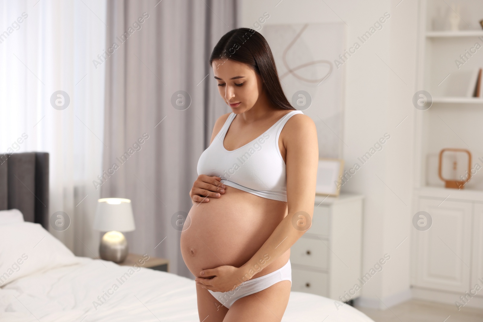 Photo of Beautiful pregnant woman wearing stylish comfortable underwear in bedroom