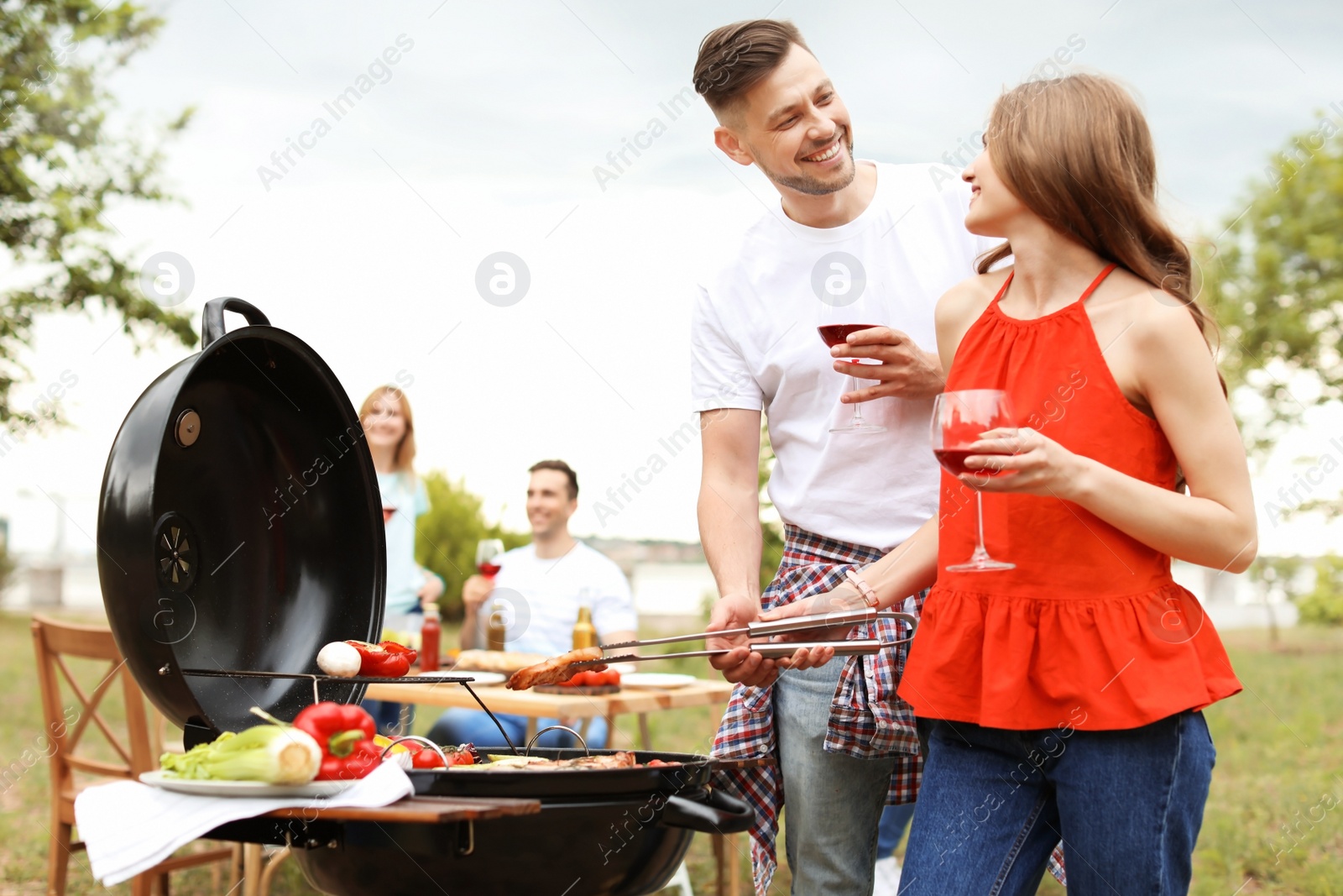 Photo of Young people having barbecue with modern grill outdoors