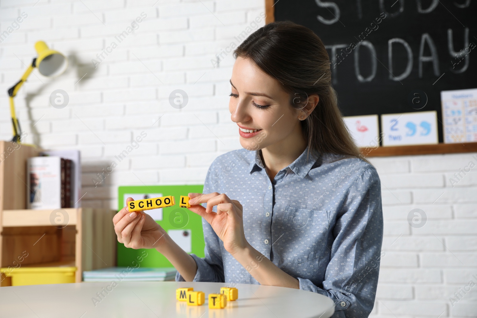 Photo of Happy female English teacher giving lesson in elementary school