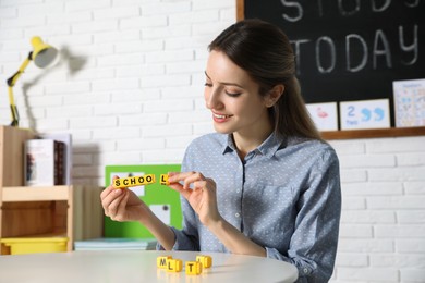 Happy female English teacher giving lesson in elementary school