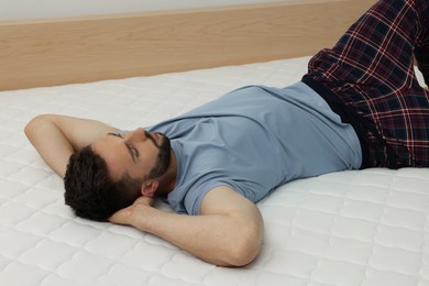 Man sleeping on bed with comfortable mattress at home