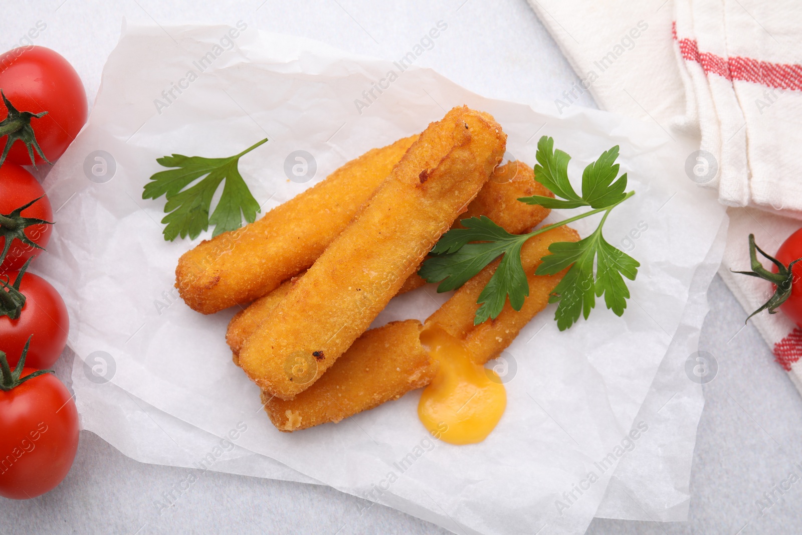 Photo of Tasty fried mozzarella sticks, tomatoes and parsley on light table, above view