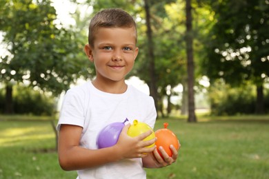 Photo of Cute little boy holding water bombs in park