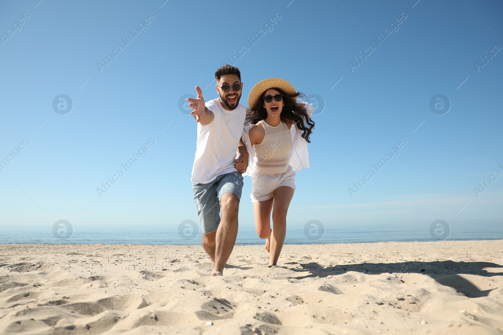 Photo of Happy young couple having fun on beach near sea. Honeymoon trip