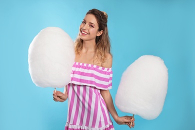Portrait of pretty young woman with cotton candy on blue background