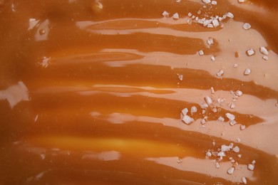 Photo of Delicious caramel sauce with sea salt as background, closeup