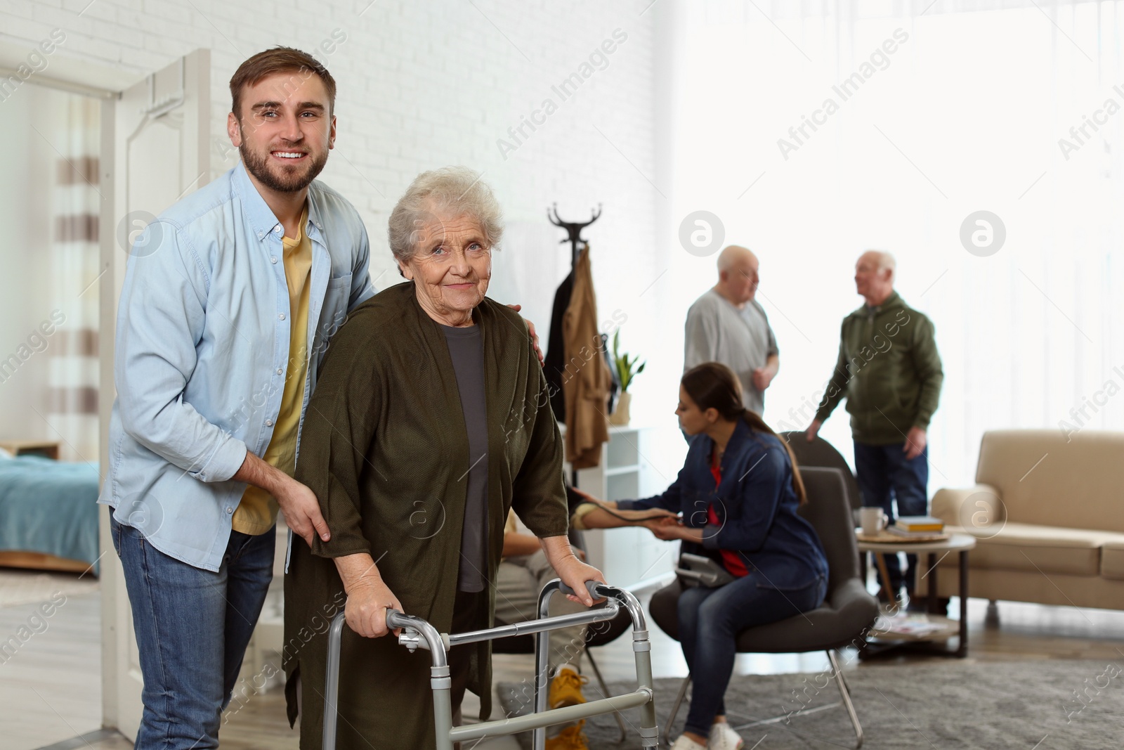 Photo of Care worker helping to elderly woman with walker in geriatric hospice