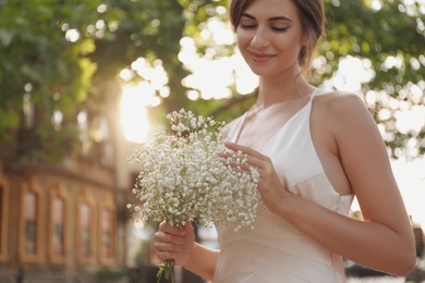 Photo of Gorgeous bride in beautiful wedding dress with bouquet outdoors