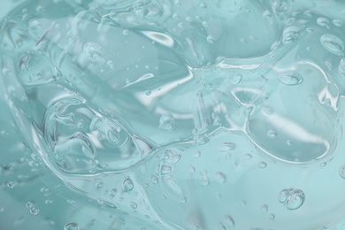 Photo of Pure transparent cosmetic gel on light blue background, closeup