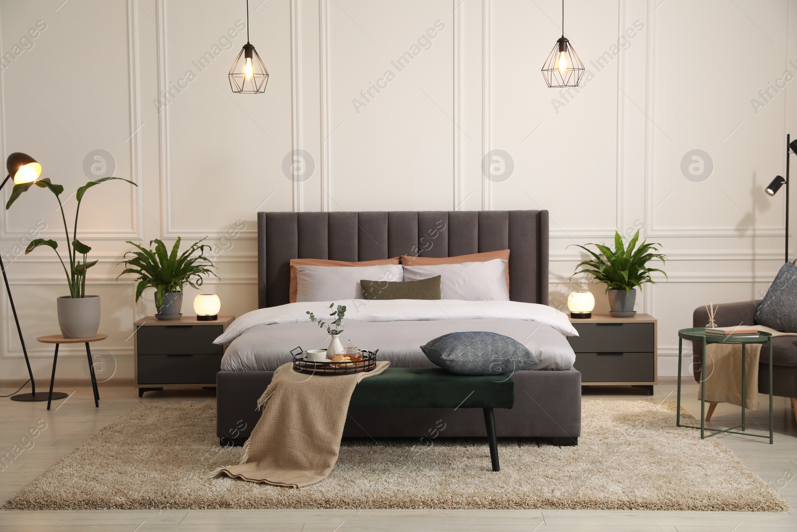 Photo of Stylish bedroom interior with large comfortable bed, armchair and ottoman