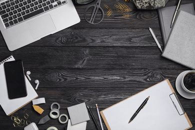 Photo of Flat lay composition with laptop. smartphone and stationery on black wooden table, space for text. Designer's workplace