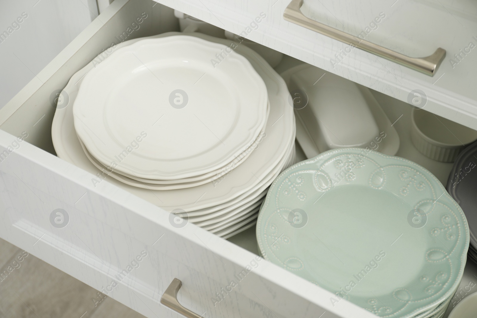 Photo of Clean plates, butter dish and bowl in drawer indoors