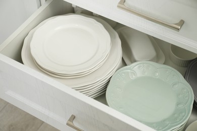 Clean plates, butter dish and bowl in drawer indoors