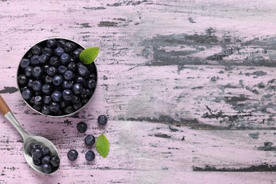 Ripe bilberries and leaves on wooden rustic table, flat lay. Space for text