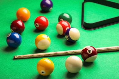 Photo of Many colorful billiard balls and cue on green table