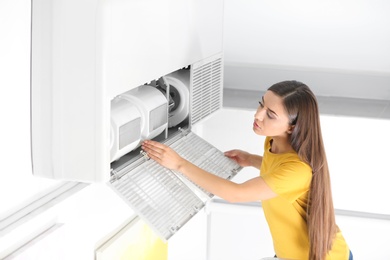 Photo of Young woman fixing air conditioner at home