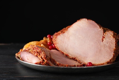 Plate with delicious ham on grey wooden table against black background