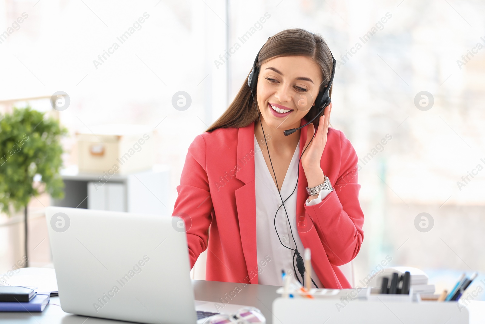 Photo of Young woman talking on phone through headset at workplace