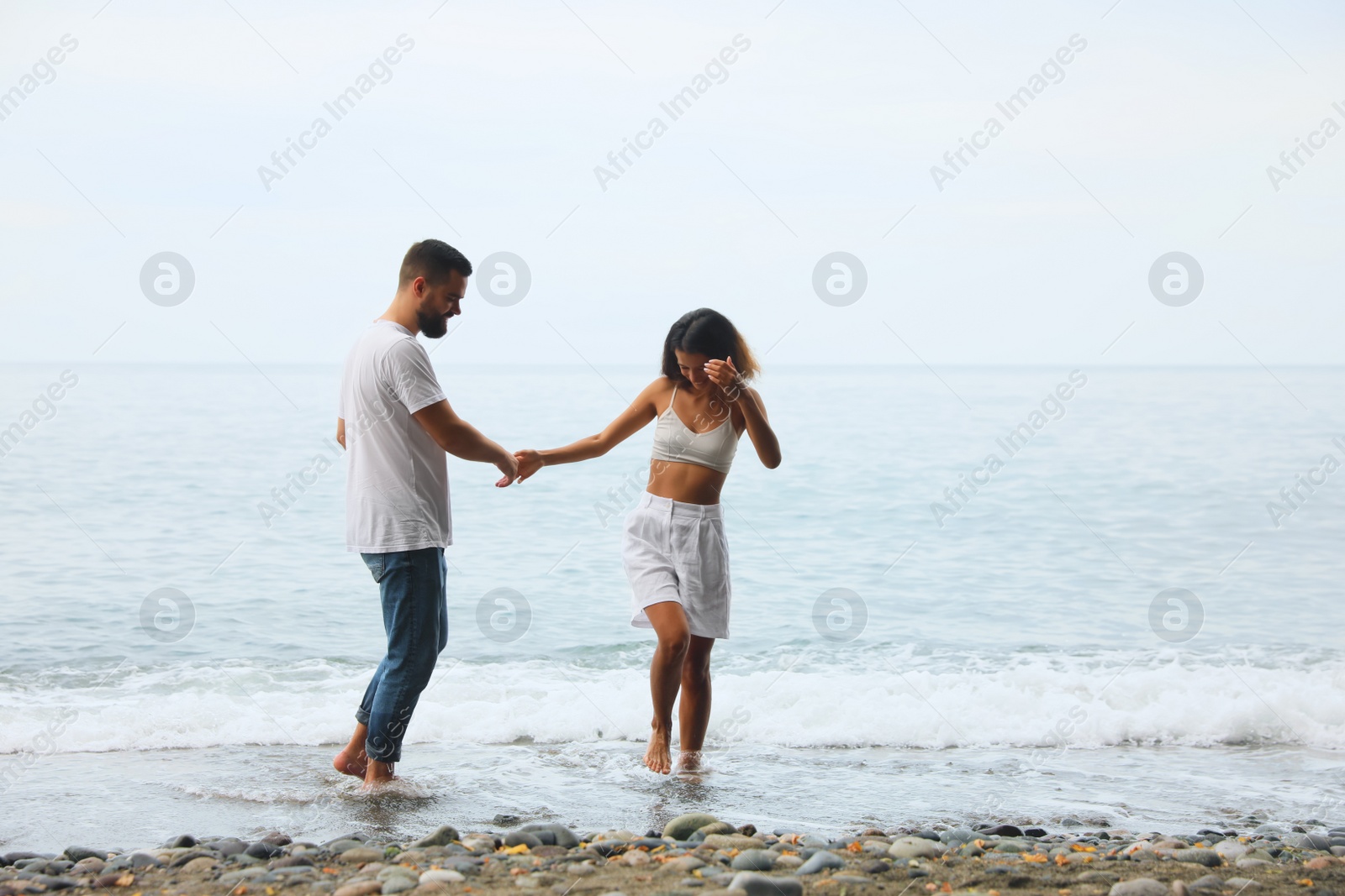 Photo of Happy young couple on beach near sea. Space for text