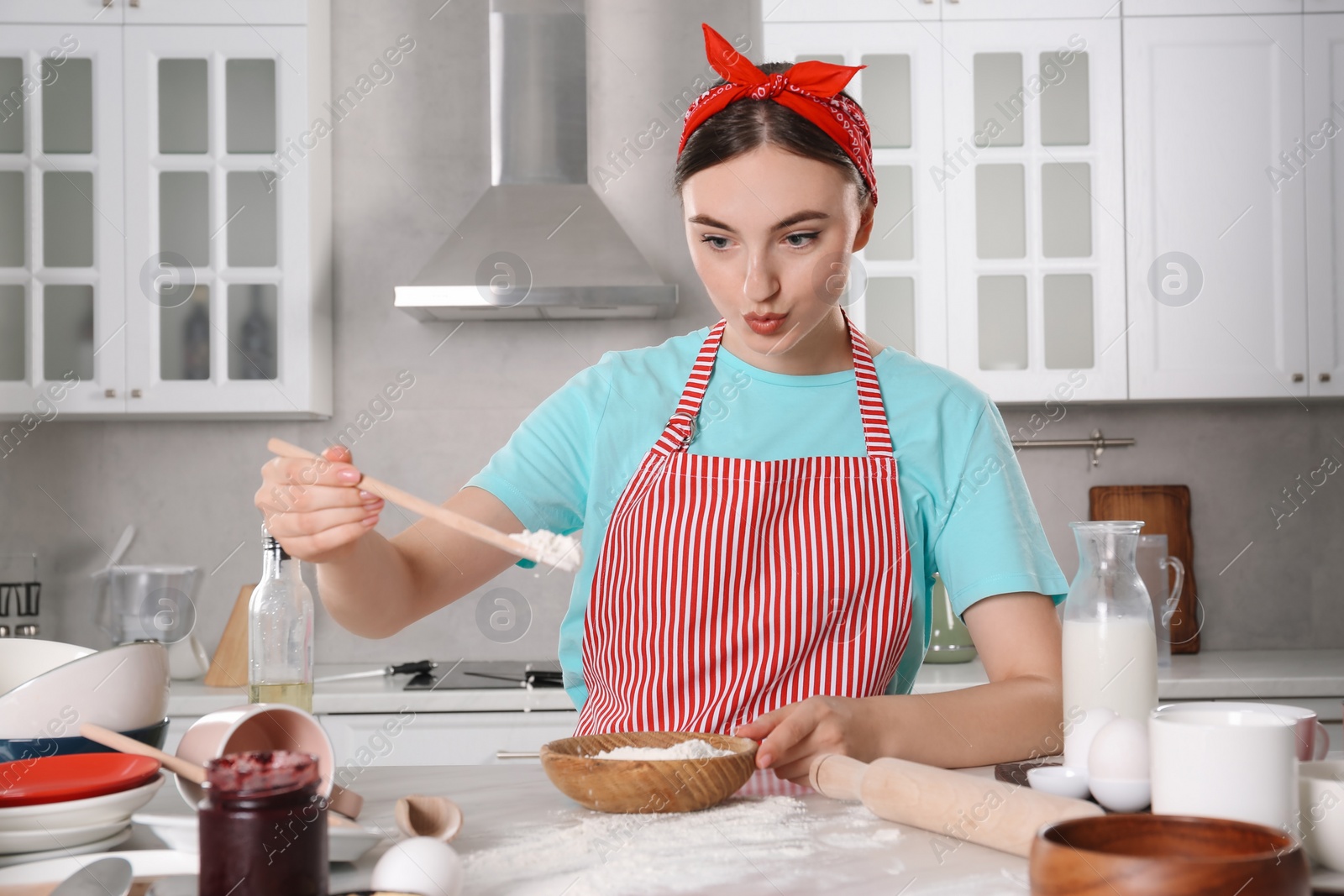 Photo of Beautiful woman cooking in kitchen. Dirty dishware, food leftovers and utensils on messy countertop