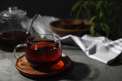 Photo of Tasty hot tea in cup on grey table, closeup. Space for text