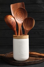 Photo of Set of kitchen utensils in holder on dark table, closeup