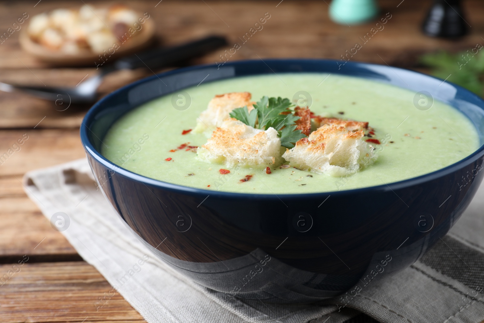 Photo of Delicious asparagus soup with croutons served on wooden table, closeup