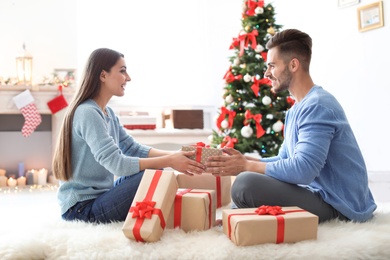 Photo of Young couple with Christmas gift at home