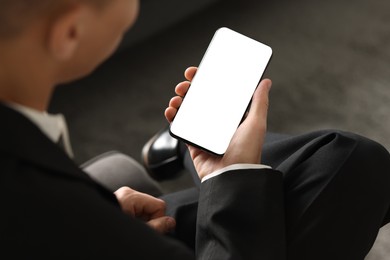 Photo of Man using smartphone with blank screen indoors, closeup. Mockup for design