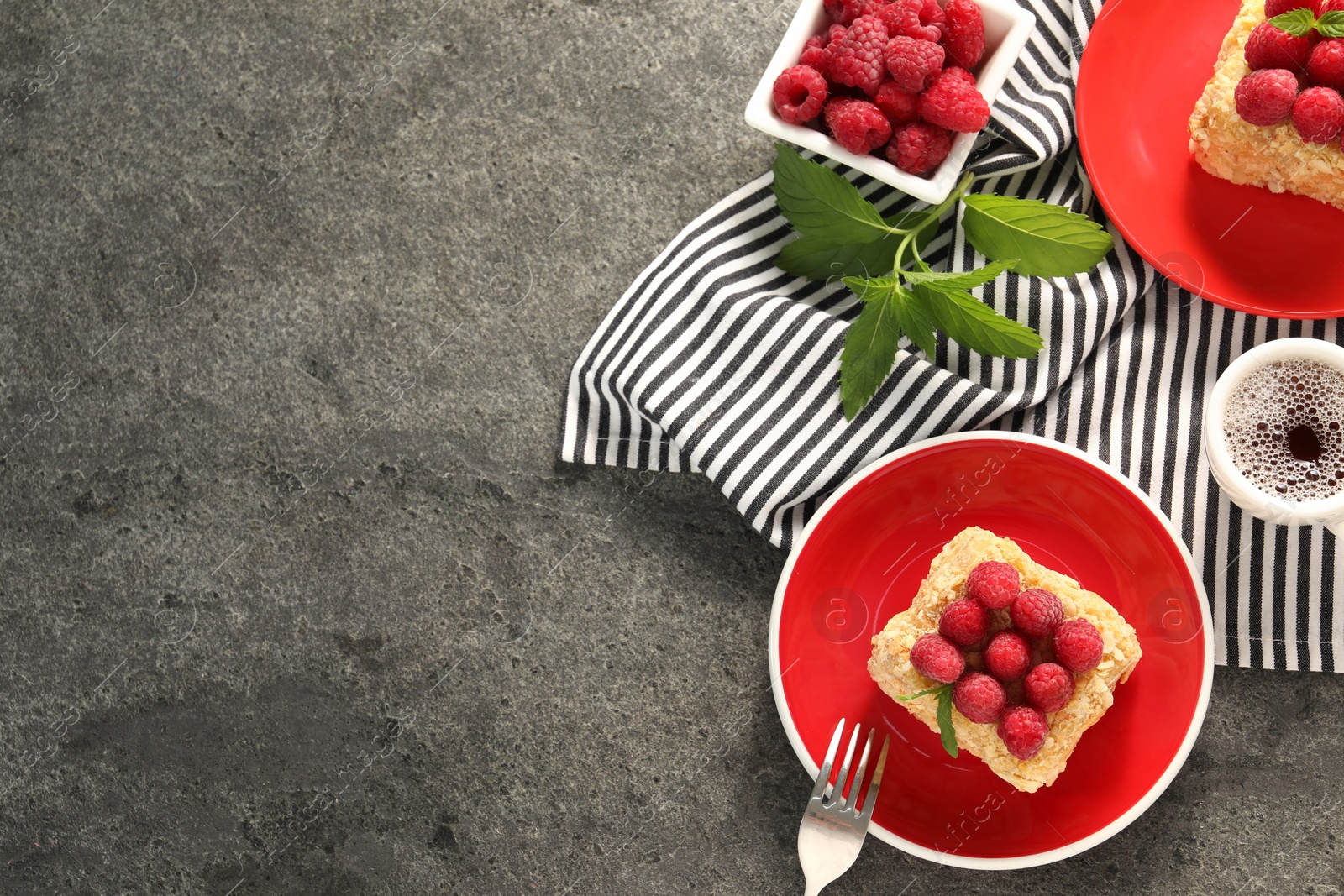 Photo of Pieces of delicious Napoleon cake with fresh raspberries served on grey table, flat lay. Space for text
