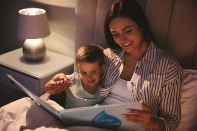 Photo of Mother reading bedtime story to her son at home