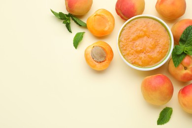 Photo of Apricot puree in bowl and fresh fruits on beige background, flat lay. Space for text