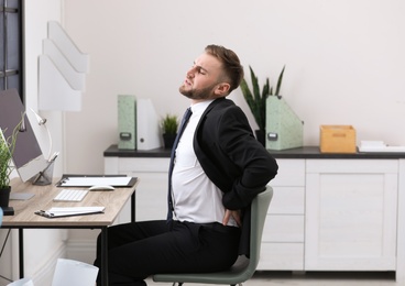 Photo of Businessman suffering from back pain at workplace
