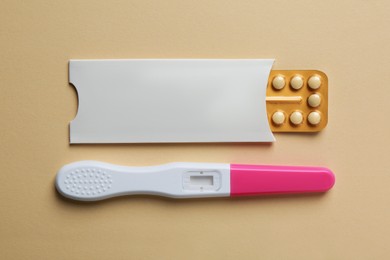 Birth control pills and pregnancy test on beige background, top view