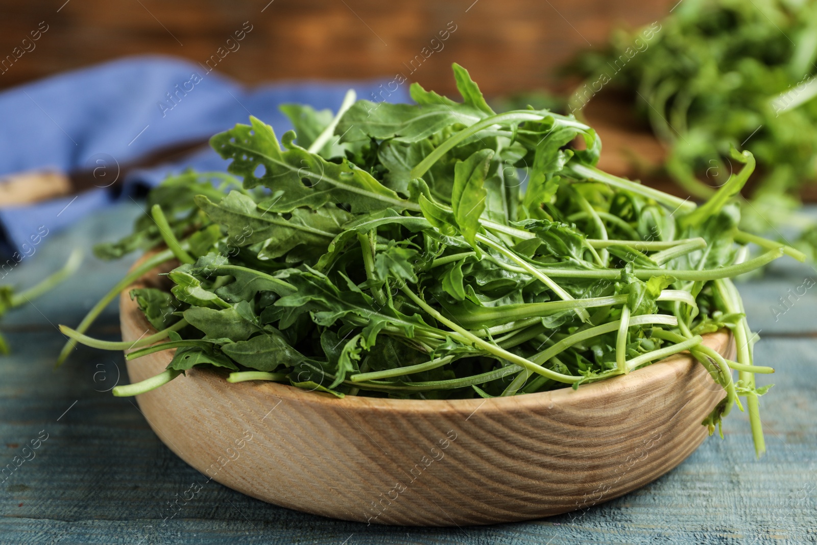 Photo of Fresh arugula on blue wooden table, closeup