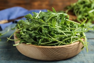 Photo of Fresh arugula on blue wooden table, closeup