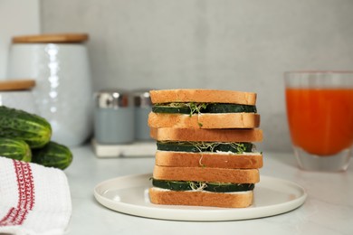 Photo of Tasty sandwiches with cucumber, cream cheese and microgreens on white table, closeup