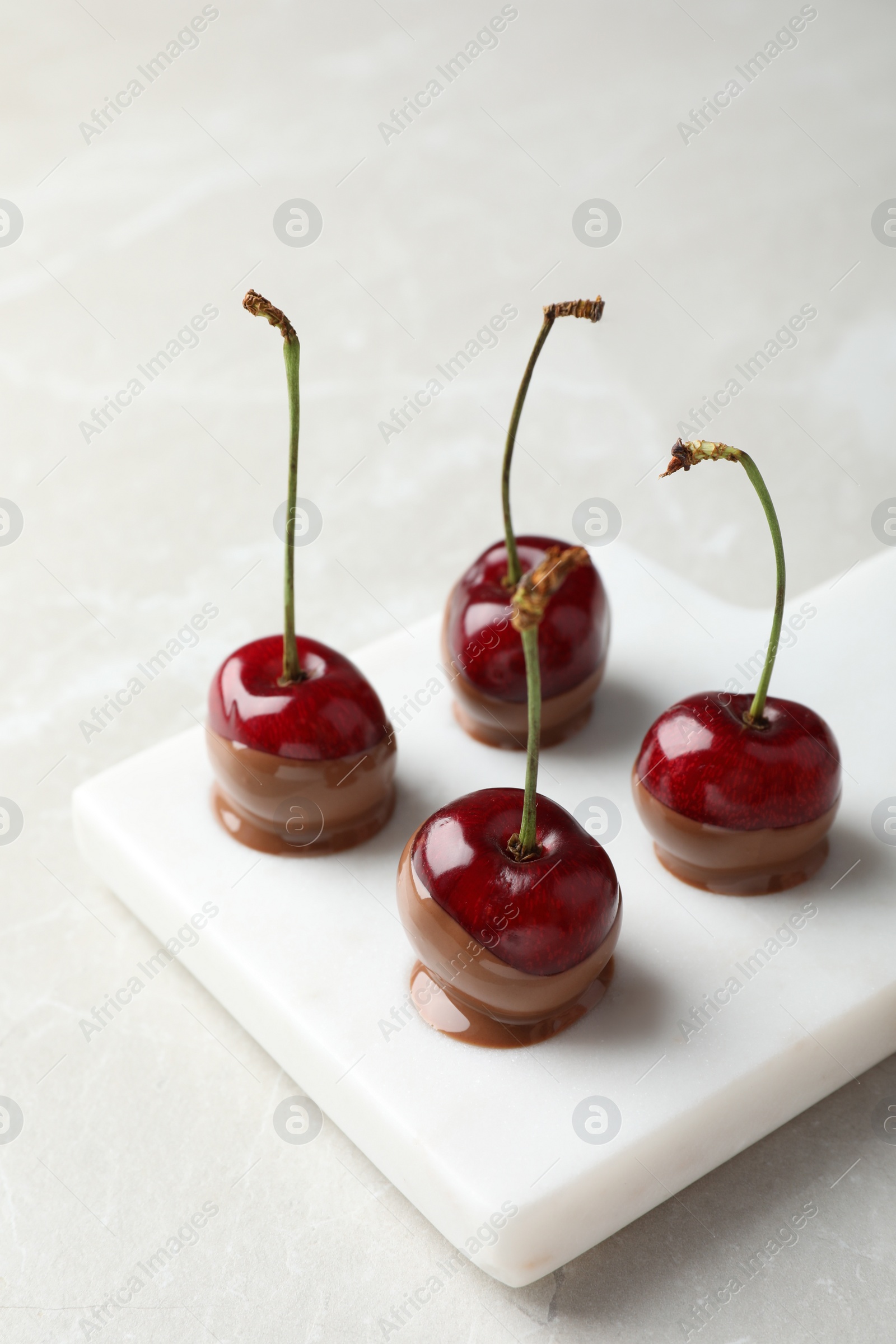 Photo of Sweet chocolate dipped cherries on white table