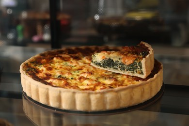 Photo of Delicious quiche with salmon and spinach on counter in bakery shop, closeup. Space for text