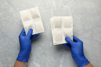 Photo of Man in gloves with mustard plasters at light grey marble table, top view