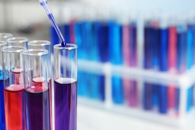 Photo of Dripping reagent into test tube with sample in chemistry laboratory, closeup. Space for text