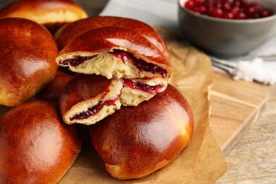 Delicious baked cranberry pirozhki on wooden table, space for text