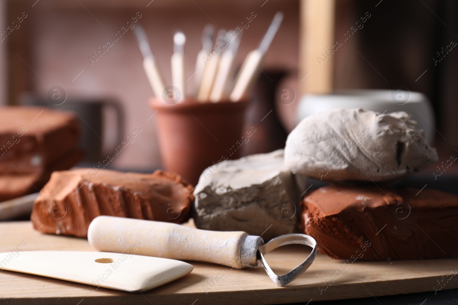 Photo of Clay and set of modeling tools on table in workshop