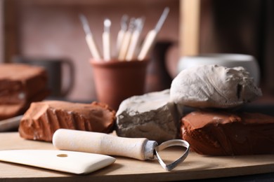 Photo of Clay and set of modeling tools on table in workshop