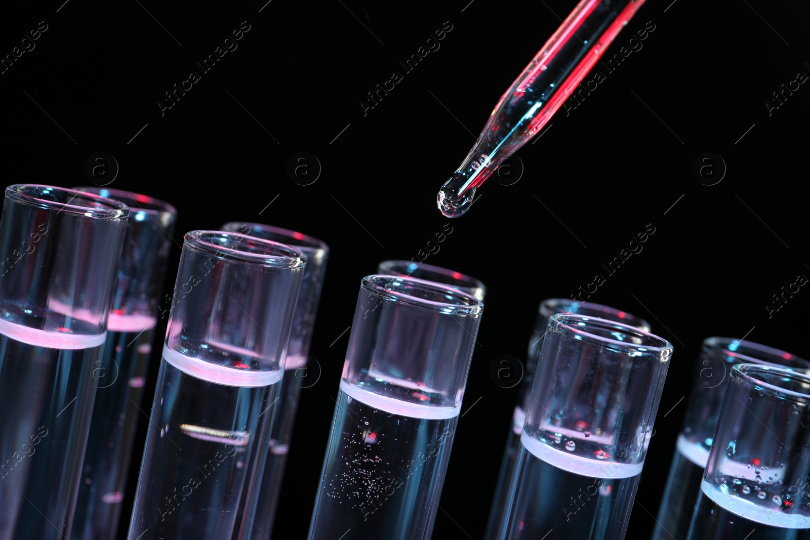 Photo of Dripping reagent into test tube on black background, closeup. Laboratory analysis