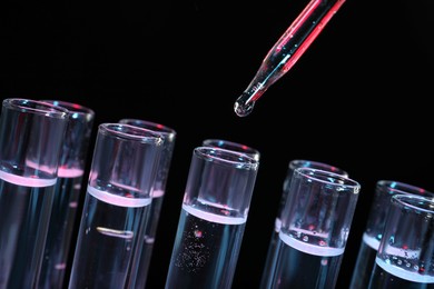 Photo of Dripping reagent into test tube on black background, closeup. Laboratory analysis