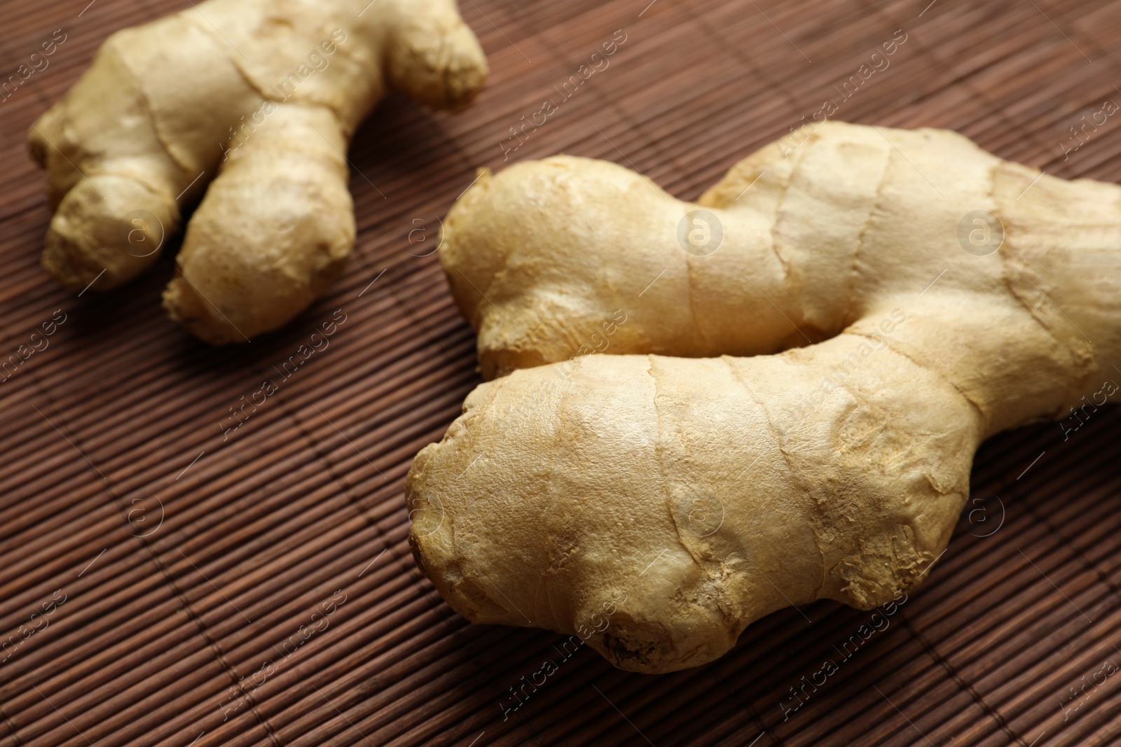 Photo of Fresh aromatic ginger on bamboo mat, closeup