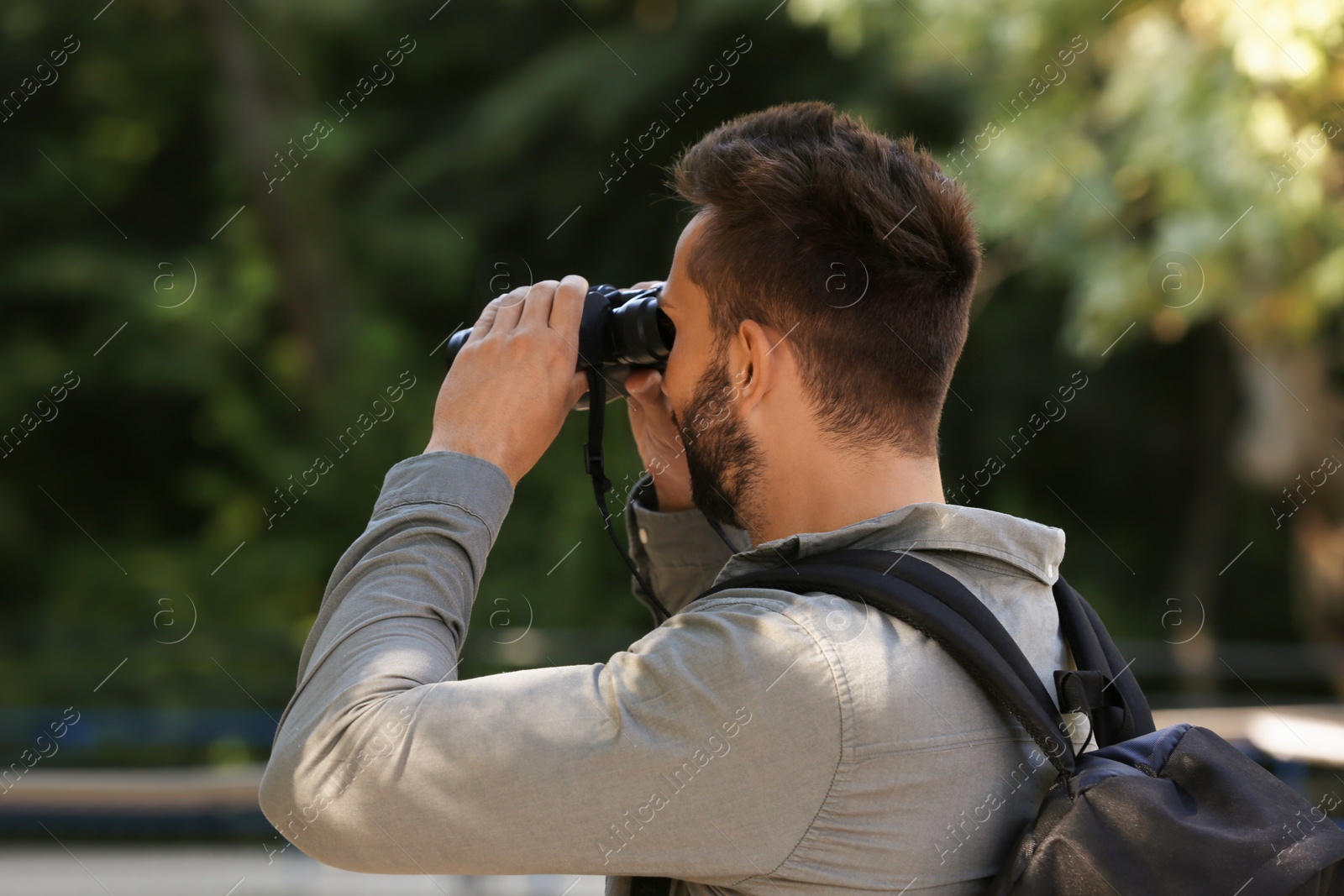 Photo of Handsome man with binoculars spending time in nature reserve