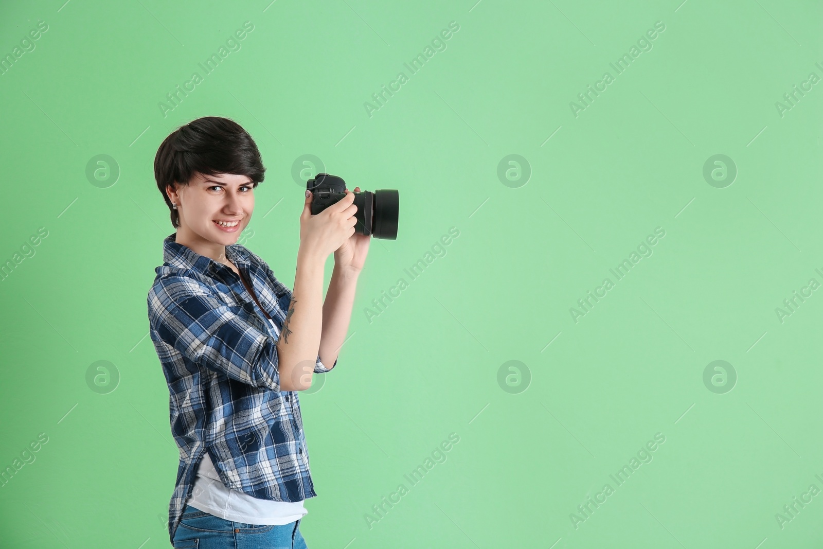 Photo of Young female photographer with camera on color background