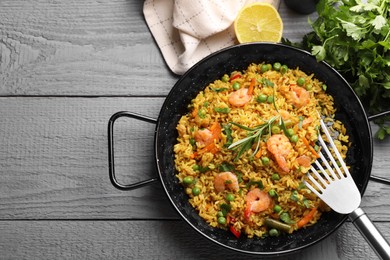 Photo of Tasty rice with shrimps and vegetables served on grey wooden table, flat lay. Space for text